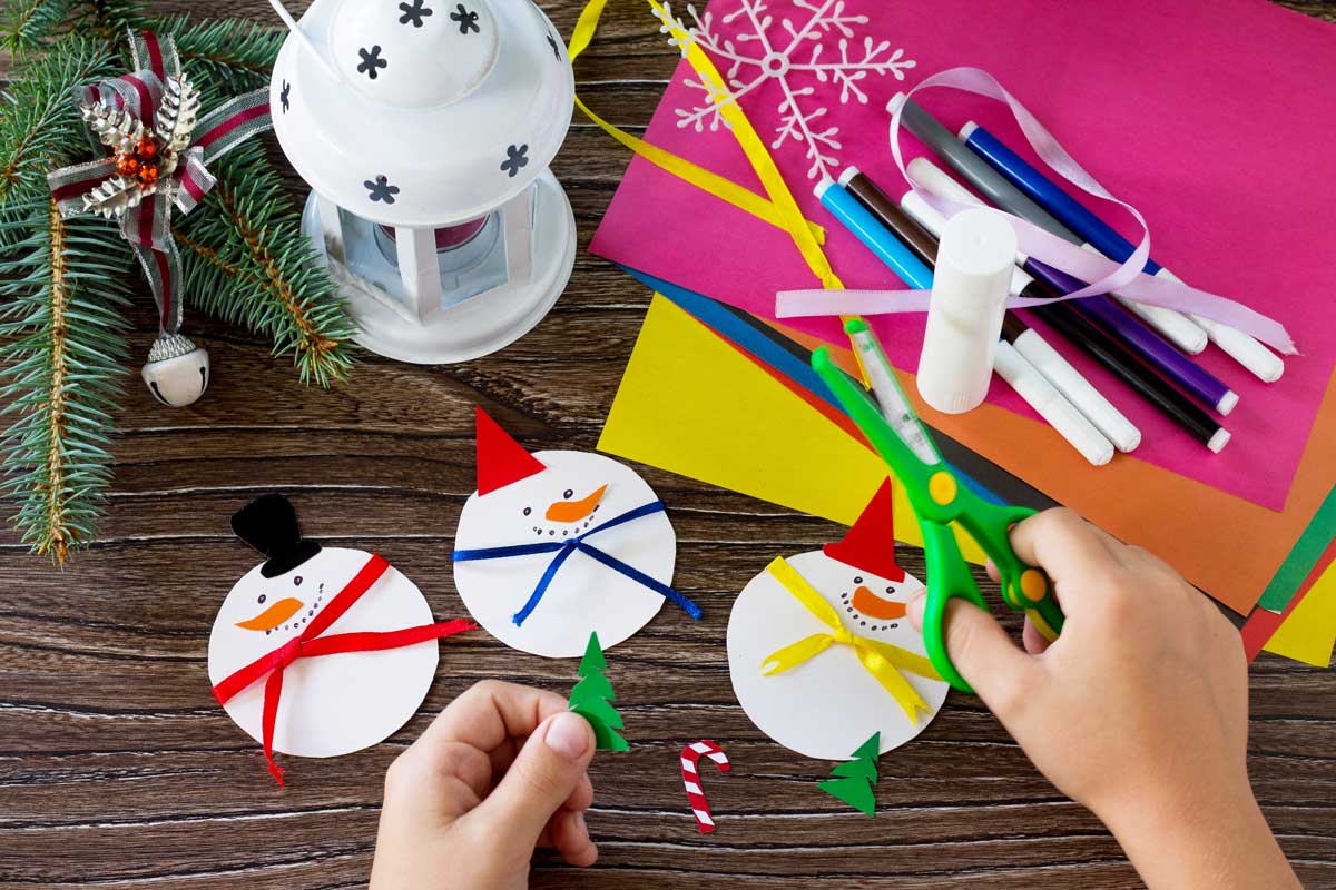 Tonpapier, Stifte, Schere auf Tisch mit Tannenzweig und Laterne