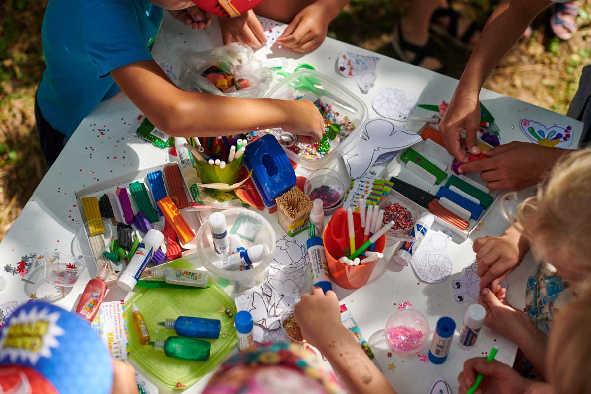 Kinder sitzen draußen am Tisch und basteln