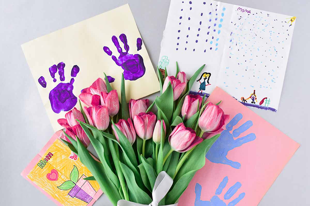 Muttertag-und-Vatertag-Bastelwelt Papier mit Handabdrücken, Blumen und Kinderzeichnung auf Tisch
