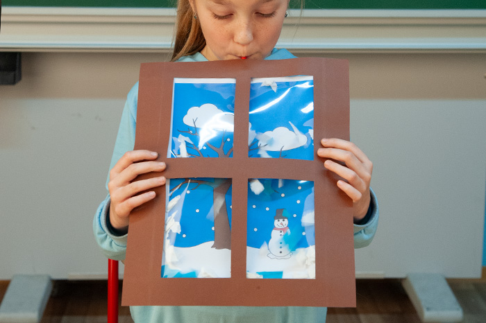 Schneegestöber basteln Kind pustet in die Bastelidee Schneegestöber