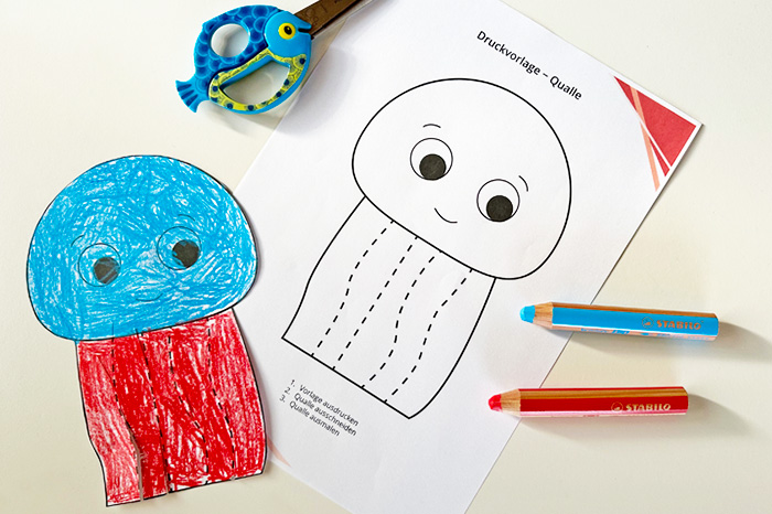 Vorlage Schneideübung Qualle Schneideübung Qualle Vorlage und ausgemaltes Beispiel mit Stift und Schere auf Tisch