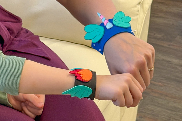Märchen-Armbänder basteln Zwei gebastelte Märchenarm-Bänder an zwei Handgelenken