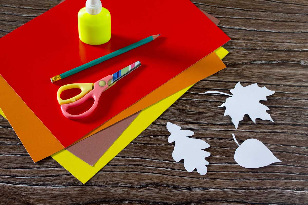 Tonpapier, Schere, Bleistift und Kleber auf Tisch