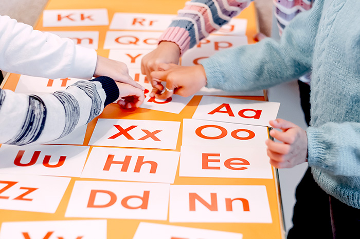 Kinder zeigen auf Karten mit Buchstaben