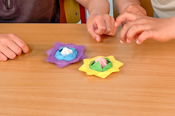 Zwei Kinder spielen mit ihren selbstgebastelten Papierkreiseln