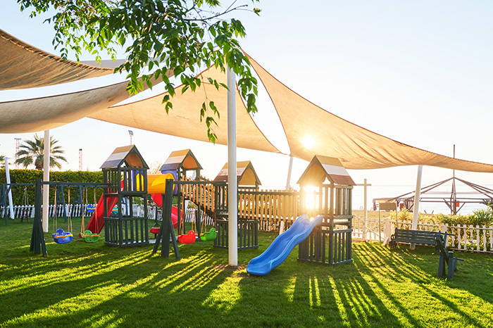 Sonnensegel im Kindergarten Ein Spielplatz wird von mehreren Sonnensegeln überspannt