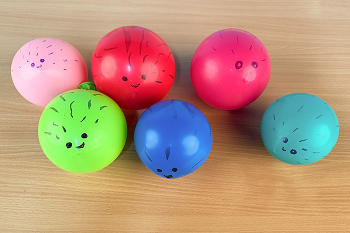 Einfaches Kinderexperiment Sechs gefüllte Luftballons aus dem Kugelfisch-Experiment liegen auf dem Tisch