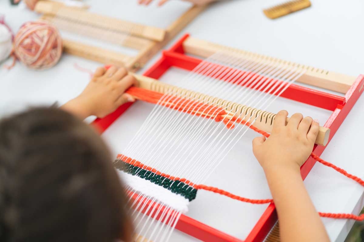 Kind webt an einem Kinder Webstuhl