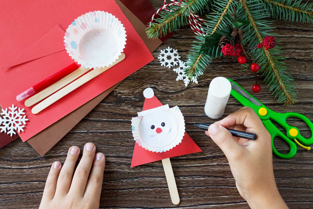 Tonpapier, Eisstiele, Schere und Tannenzweig auf Tisch