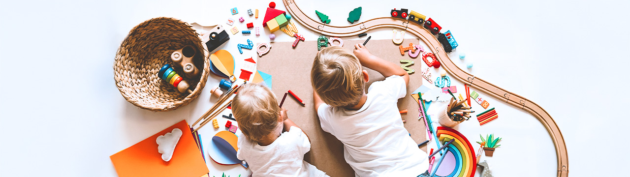 Spielzeug Zwei Kinder liegen in einer Menge Spielzeug und spielen damit