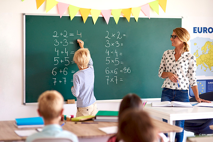 ein Schüler löst Matheaufgaben an der Tafel