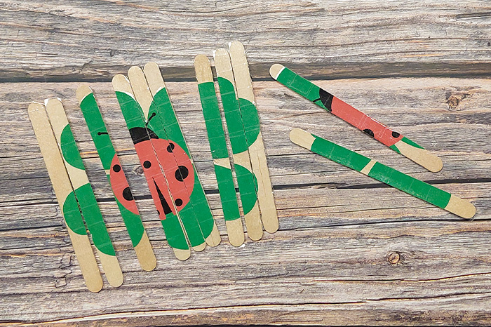 Silvester Puzzle Selbstgebasteltes Puzzle aus Eisstielen mit einem Marienkäfer und Kleeblatt-Motiv