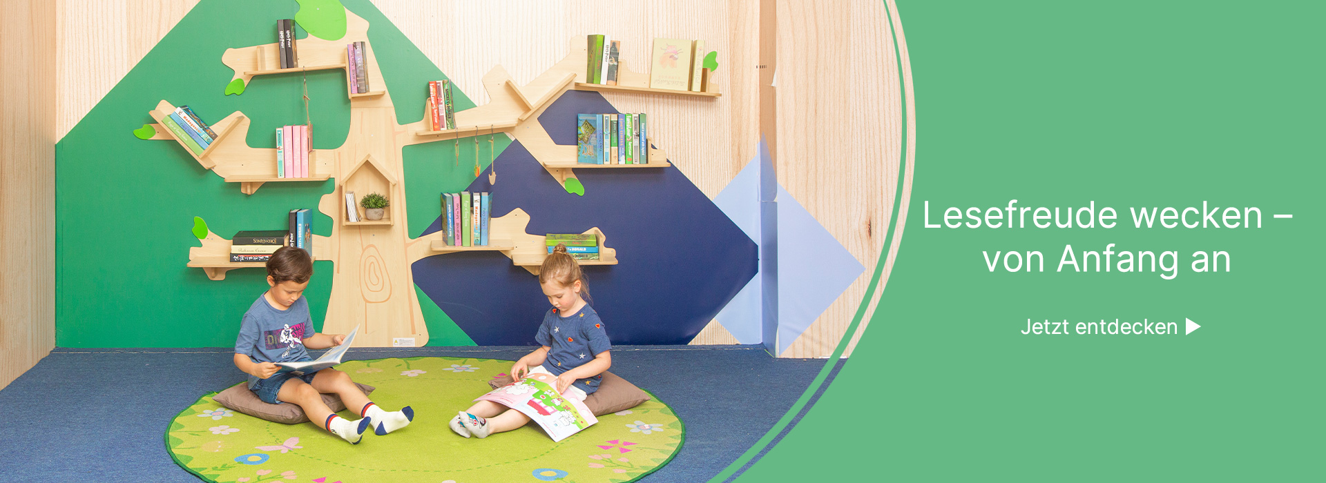 Zwei Kinder sitzen in der Leseecke under dem baumförmigen Bücherregal