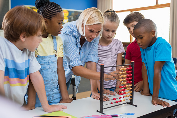Kinder stehen mit Lehrerin an einem Abakus