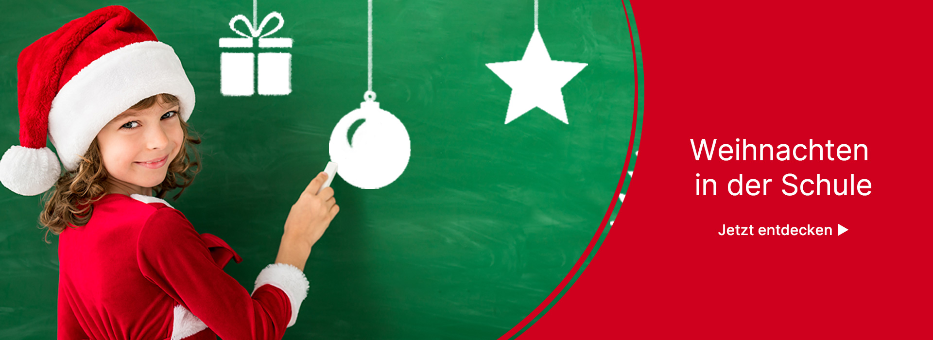 Schülerin mit Weihnachtsmütze malt mit Kreide Weihnachtssymbole an die Tafel